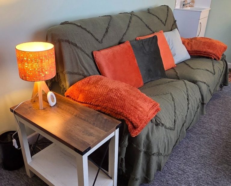 image shows 2 people on a sofa with a cuppa tea for in person therapy